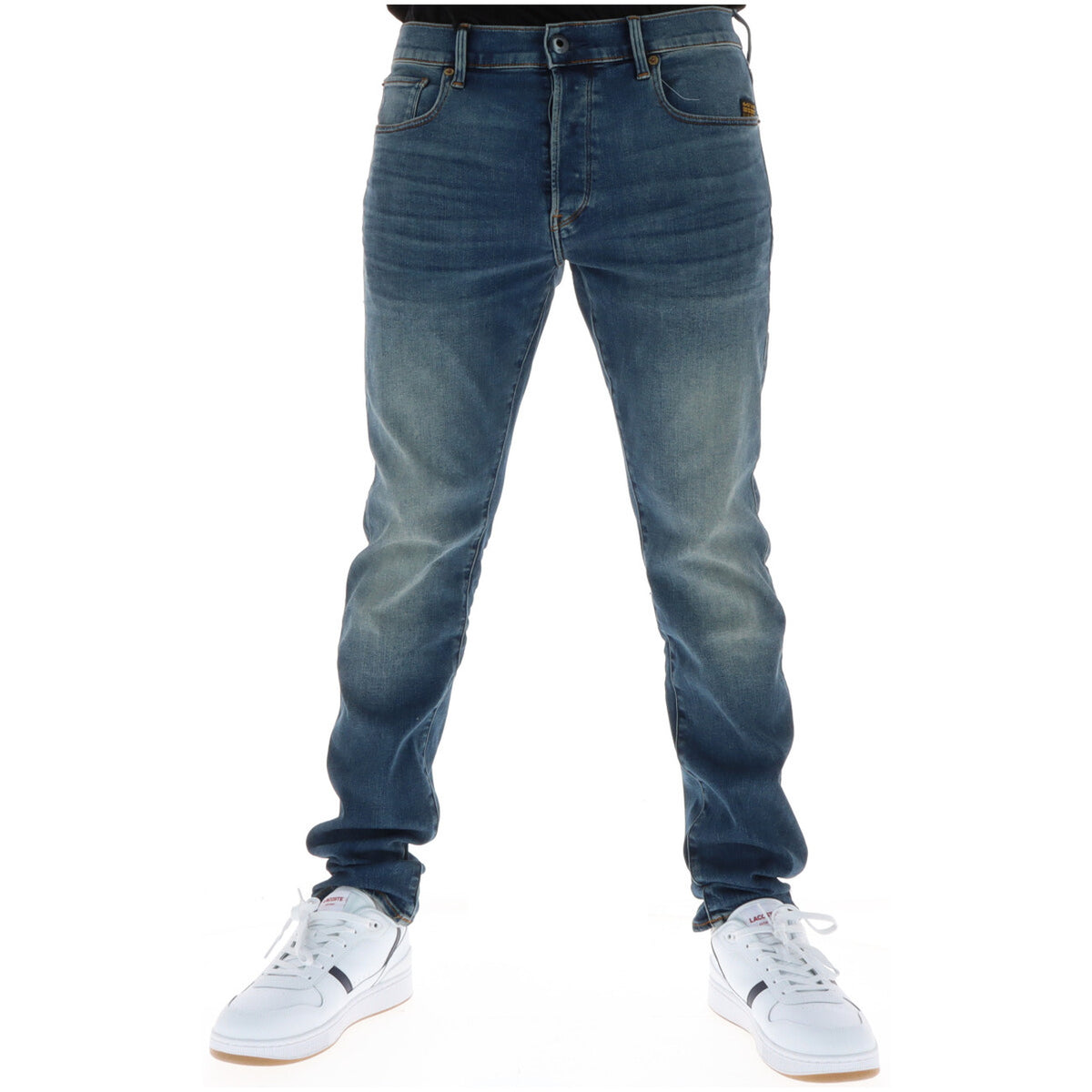 Image 1 : Jean slim G-Star homme en denim bleu effet usé porté avec des sneakers blanches Lacoste, vue frontale — Delvale