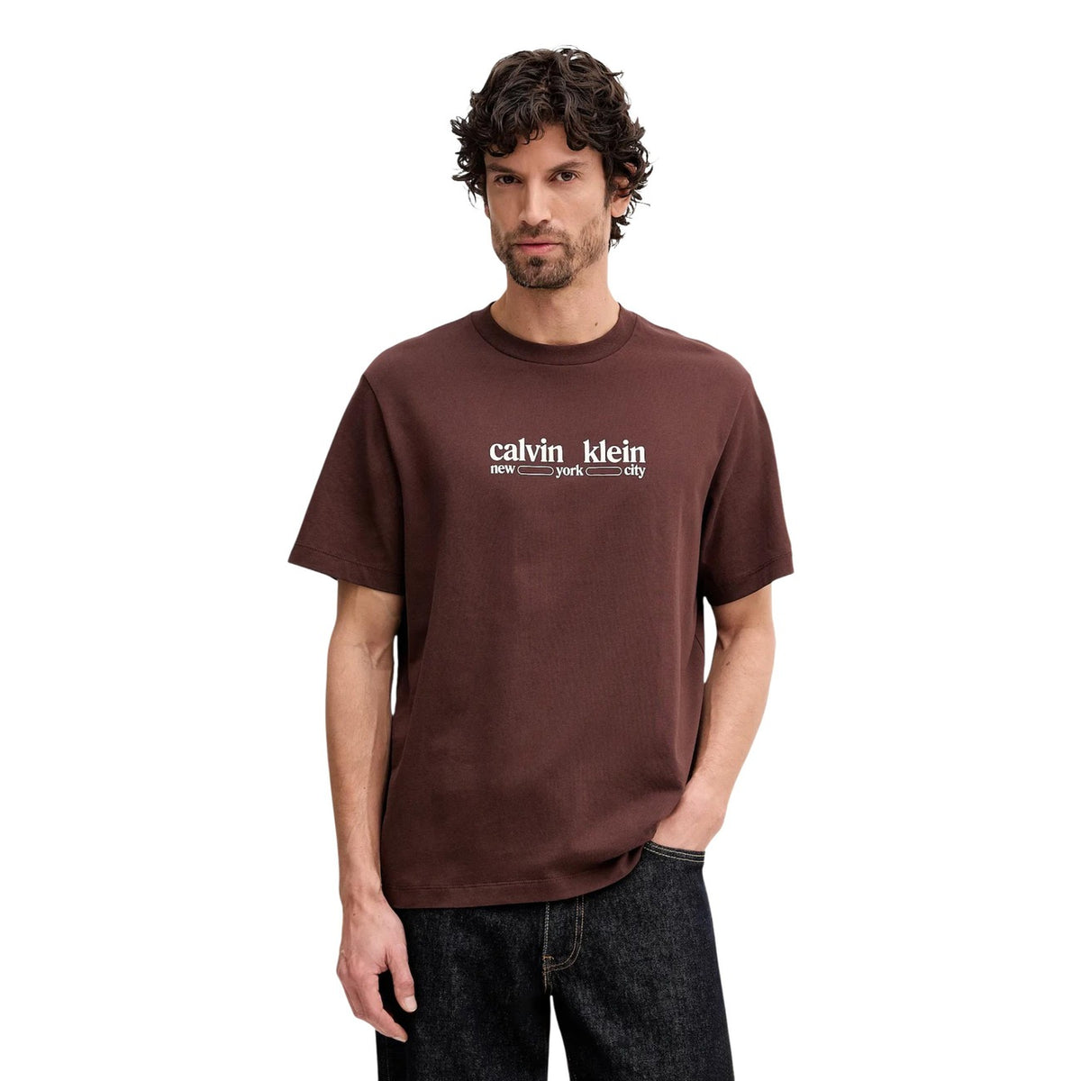 Image 1 : Homme portant un t-shirt Calvin Klein Jeans marron avec logo New York City sérigraphié en blanc sur la poitrine, coupe oversize col rond — Delvale