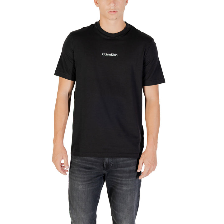 Image 1 : T-shirt noir Calvin Klein Sport homme à col rond et logo blanc central, porté de face avec un jean gris — Delvale