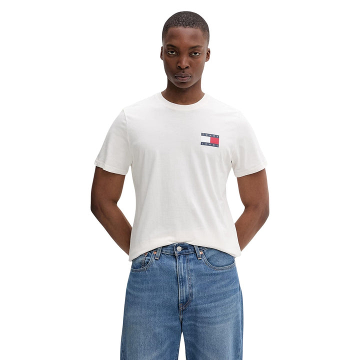 Image 1 : Homme portant un t-shirt blanc Tommy Hilfiger Jeans slim fit avec logo flag brodé sur la poitrine gauche, associé à un jean bleu — Delvale