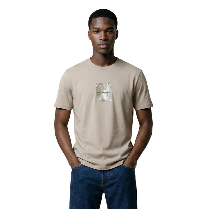 Image 1 : Homme portant le t-shirt Armani Exchange beige à col rond avec imprimé palmier centré sur la poitrine, associé à un jean bleu foncé — Delvale