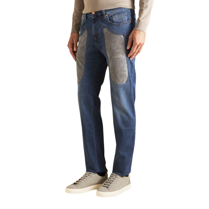 Image 1 : Jean Jeckerson homme bleu moyen avec larges patches en suédine grise sur les cuisses et hanches, coupe droite, porté avec sneakers beiges et pull col roulé crème — Delvale