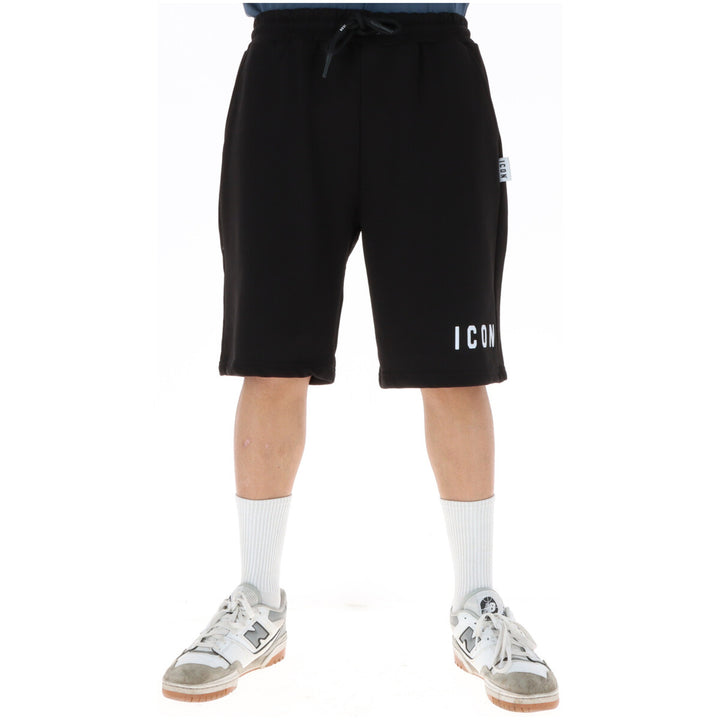 Image 1 : Bermuda jogging Icon homme noir avec logo ICON imprimé blanc sur la jambe droite, porté avec des sneakers New Balance blanches — Delvale