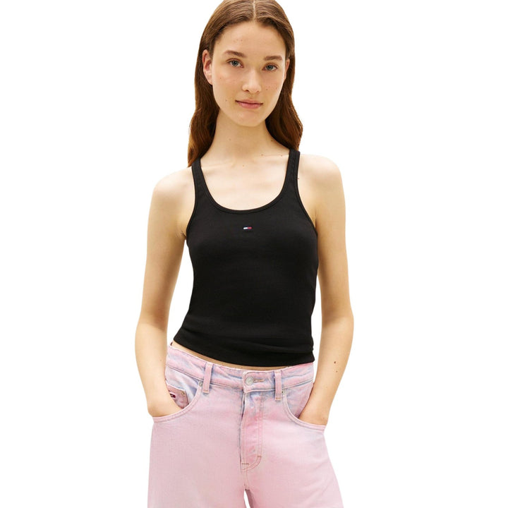 Image 1 : Femme portant un débardeur noir côtelé Tommy Hilfiger Jeans avec logo brodé signature au centre, associé à un jean rose — Delvale