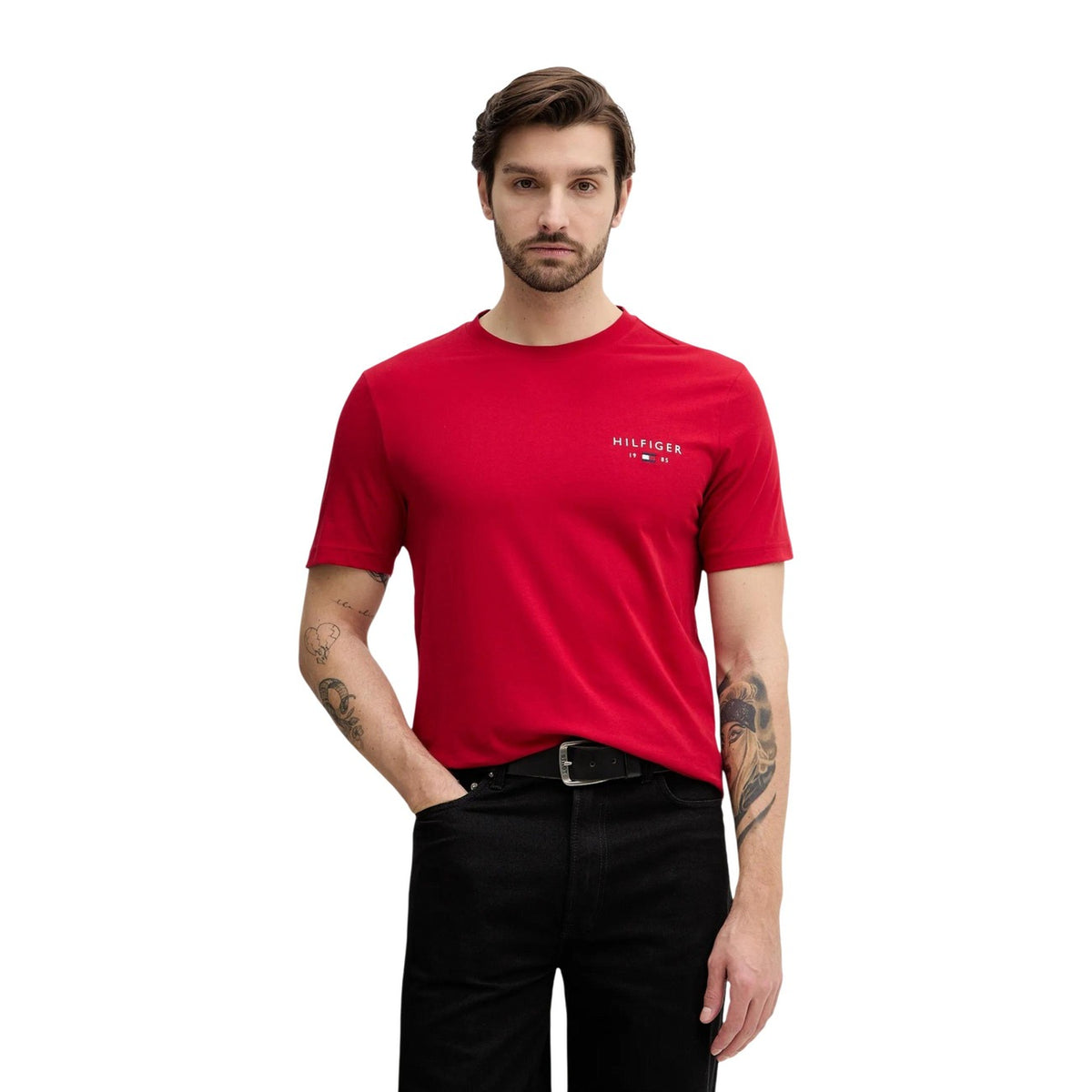 Image 1 : Homme portant un t-shirt rouge Tommy Hilfiger Jeans avec logo Hilfiger 1985 brodé sur la poitrine gauche, fond blanc — Delvale