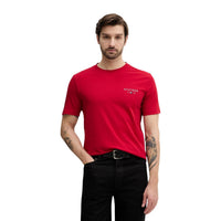 Image 1 : Homme portant un t-shirt rouge Tommy Hilfiger Jeans avec logo Hilfiger 1985 brodé sur la poitrine gauche, fond blanc — Delvale