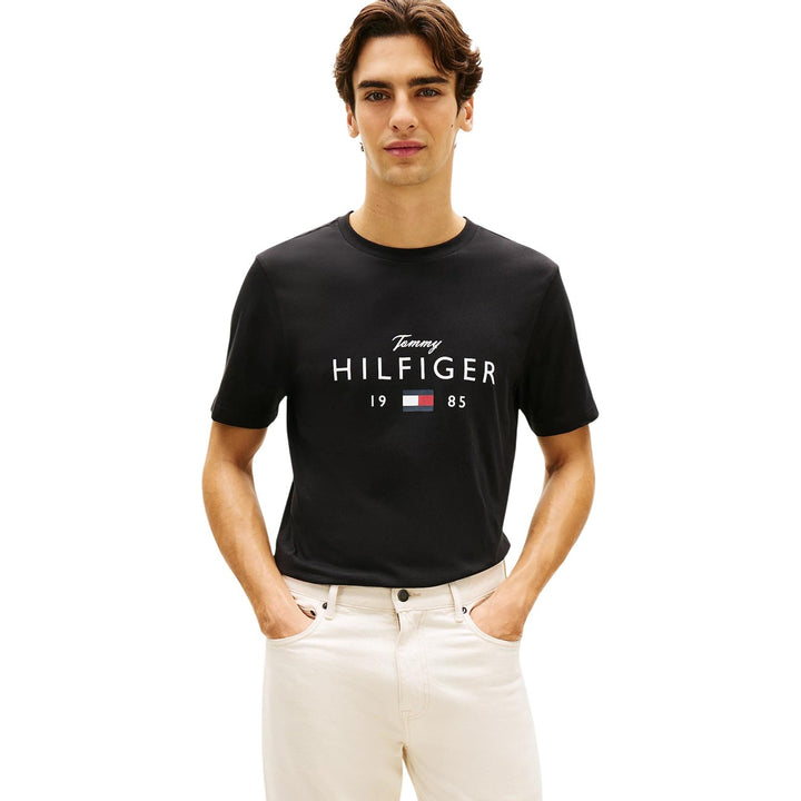 Image 1 : T-shirt noir Tommy Hilfiger Jeans homme avec logo signature imprimé en blanc sur la poitrine, porté par un homme brun sur fond blanc — Delvale