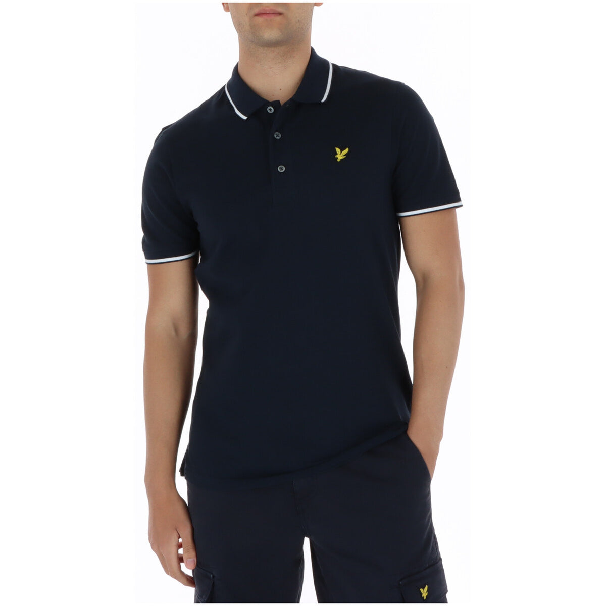 Image 1 : Polo homme Lyle & Scott en coton piqué marine, liserés blancs au col et aux poignets, logo aigle brodé doré sur la poitrine, porté par un homme — Delvale