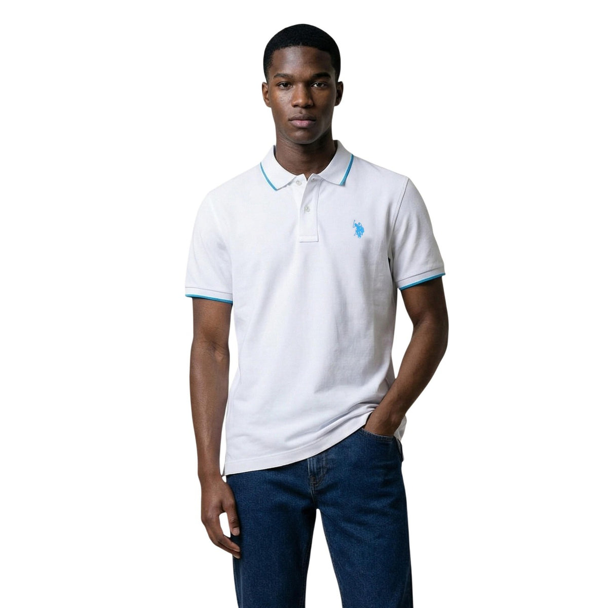 Image 1 : Homme portant un polo blanc U.S. Polo Assn. à manches courtes avec liserés bleus sur le col et les poignets, logo brodé sur la poitrine, associé à un jean brut — Delvale