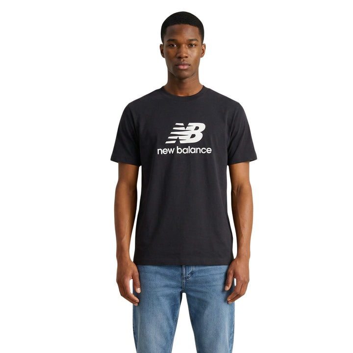 Image 1 : Homme portant le t-shirt New Balance noir à logo imprimé blanc, col rond, manches courtes, porté avec un jean bleu clair — Delvale