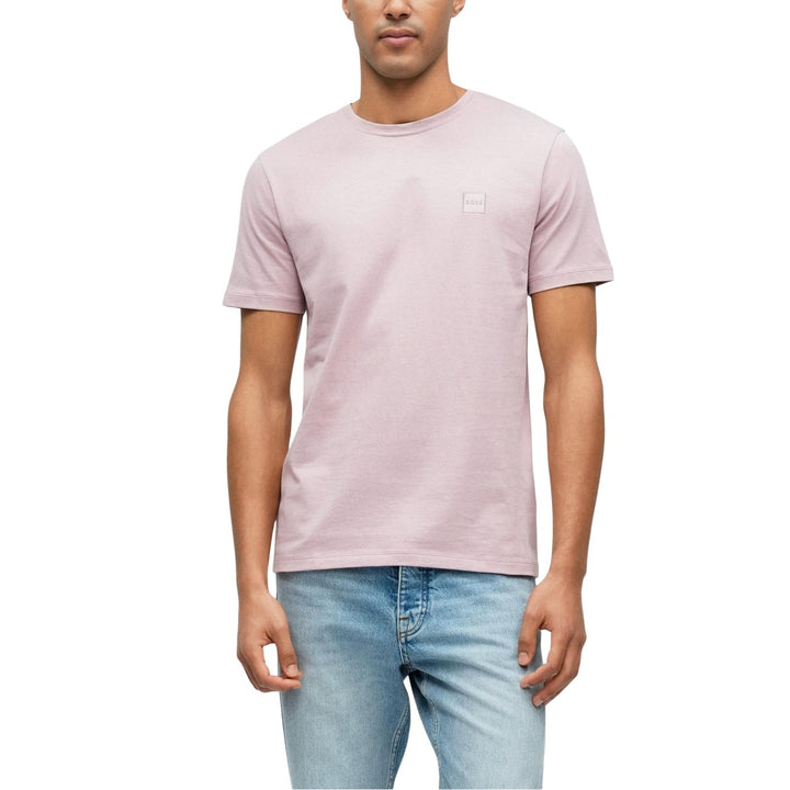 Image 1 : T-shirt Boss homme rose poudré avec patch carré ton sur ton, porté avec un jean clair, vue trois quarts — Delvale