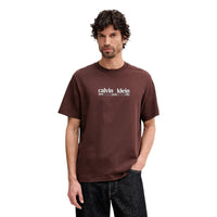 Image 1 : Homme portant un t-shirt Calvin Klein Jeans marron avec logo New York City sérigraphié en blanc sur la poitrine, coupe oversize col rond — Delvale