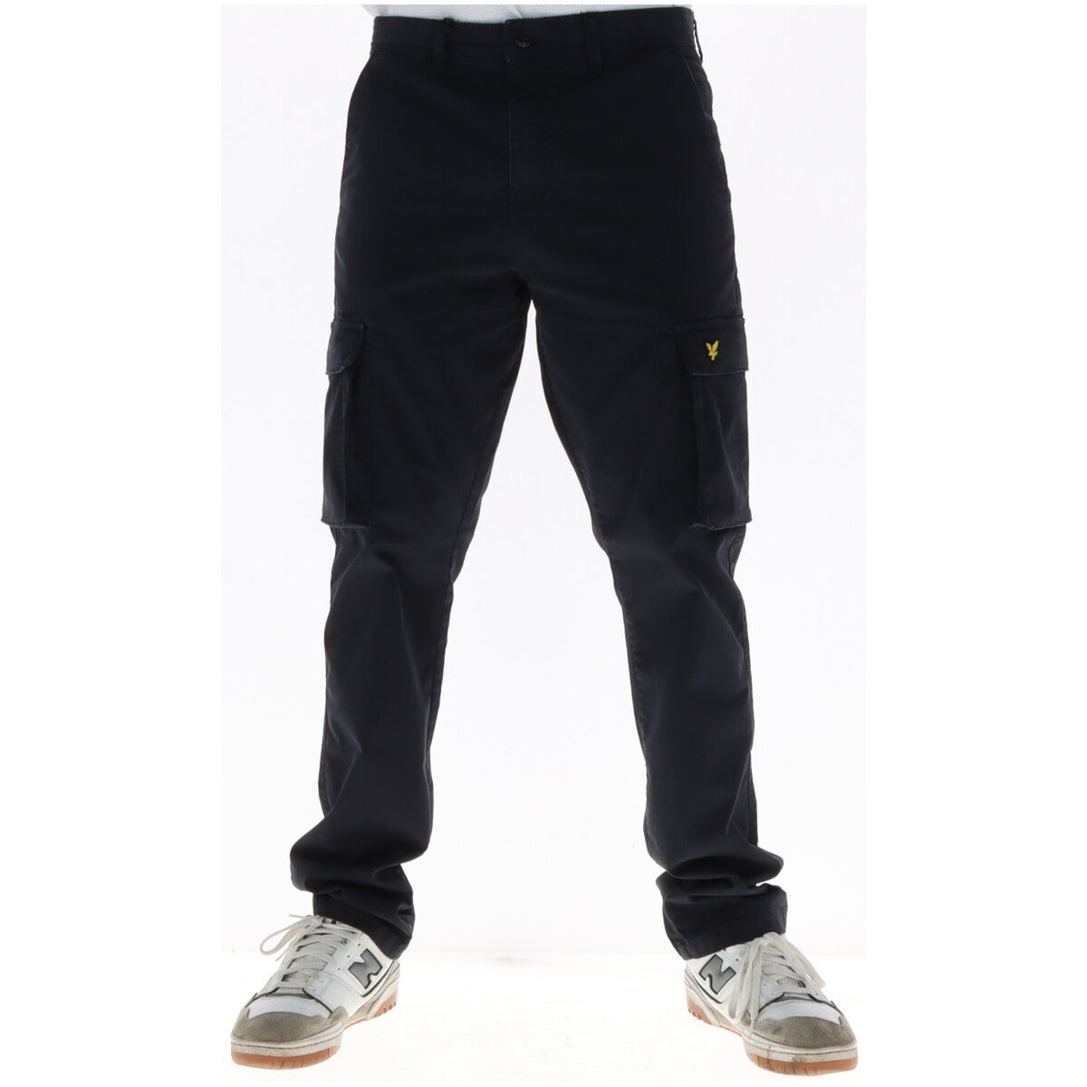 Image 1 : Pantalon cargo Lyle & Scott homme bleu marine, vue frontale avec poches latérales et logo aigle doré, porté avec sneakers New Balance — Delvale