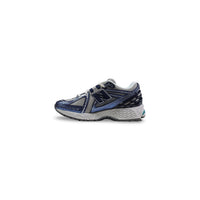 Image 3 : Détail construction New Balance 1906R femme, logo N brodé marine sur fond argenté — Delvale