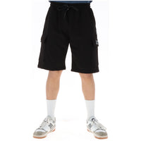 Image 1 : Bermuda cargo Icon homme noir en molleton, poches latérales à rabat et cordon de serrage, porté avec baskets New Balance blanches — Delvale