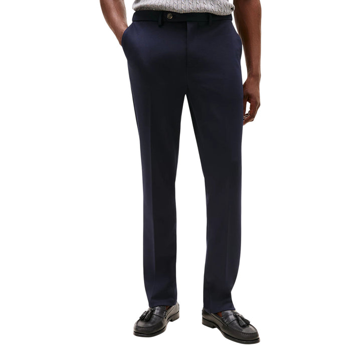 Image 1 : Pantalon habillé Tommy Hilfiger homme coupe droite bleu marine porté avec un pull torsadé gris et des mocassins noirs à glands — Delvale