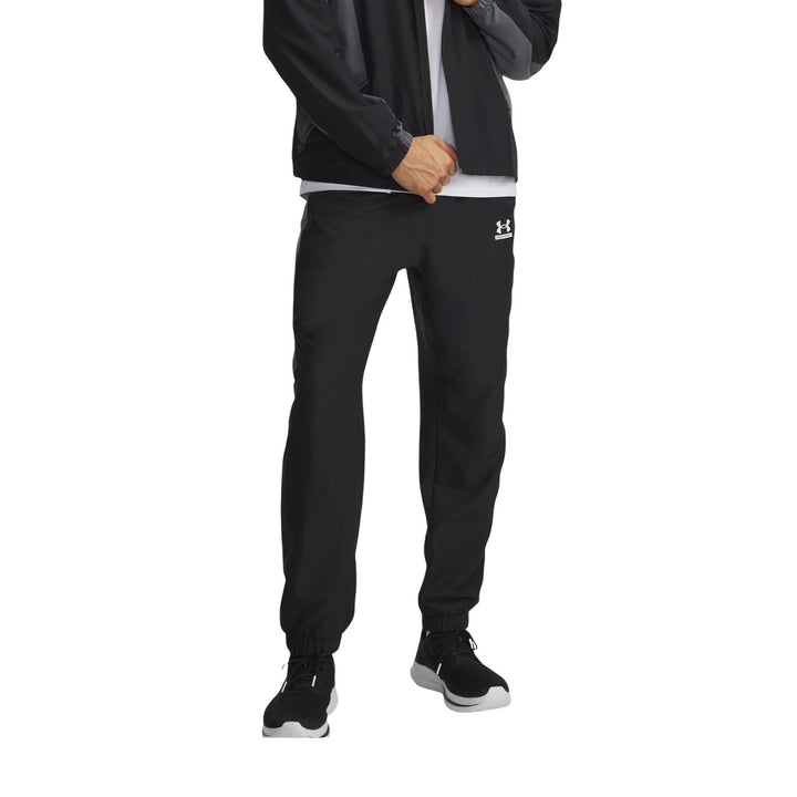 Pantalon technique Under Armour homme noir et gris porté de face avec veste assortie, coupe droite et chevilles resserrées