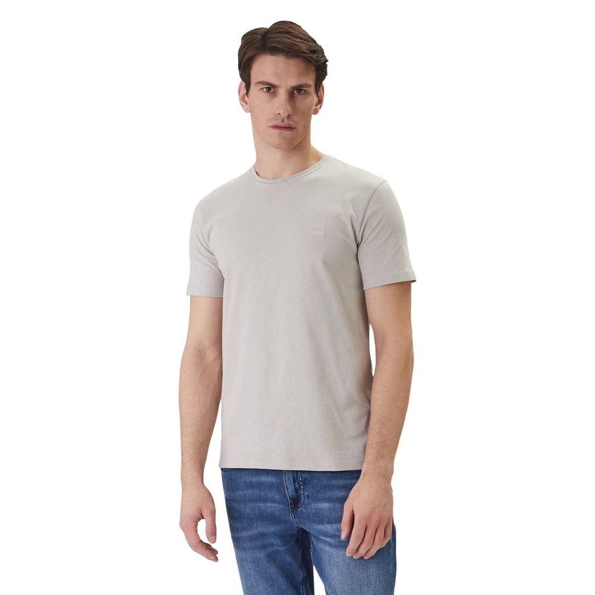 Image 1 : Homme portant un t-shirt Boss col rond gris clair avec patch logo ton sur ton sur la poitrine, associé à un jean bleu — vue de trois quarts — Delvale