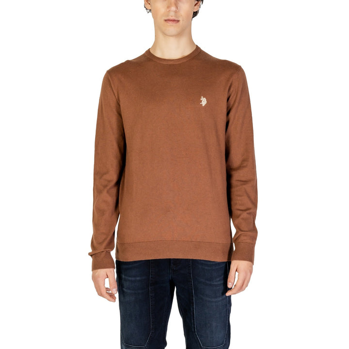 Image 1 : Pull col rond homme U.S. Polo Assn. en coloris camel avec logo cavalier brodé blanc sur la poitrine gauche, porté avec un jean brut — Delvale