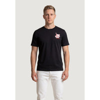 Image 1 : T-shirt New Balance homme noir à col rond avec imprimé graphique rouge et blanc sur la poitrine, porté par un homme aux cheveux blonds sur fond blanc — Delvale