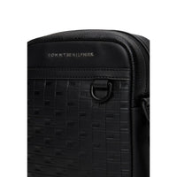 Image 3 : Sacoche Tommy Hilfiger homme noir monogramme TH gaufré relief bande grainée inscription métal sombre gros plan — Delvale
