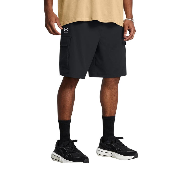 Bermuda cargo Under Armour homme noir porté de face, coupe ample au genou avec logo blanc sur la cuisse gauche