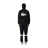 Image 2 : Ensemble jogging Lacoste homme noir, détail des bandes blanches sur la veste et le bas de survêtement, logo crocodile visible — Delvale