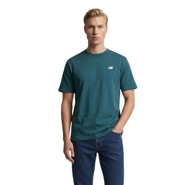 Image 1 : Homme portant le t-shirt New Balance Essential vert col rond avec logo NB brodé, associé à un jean brut — Delvale