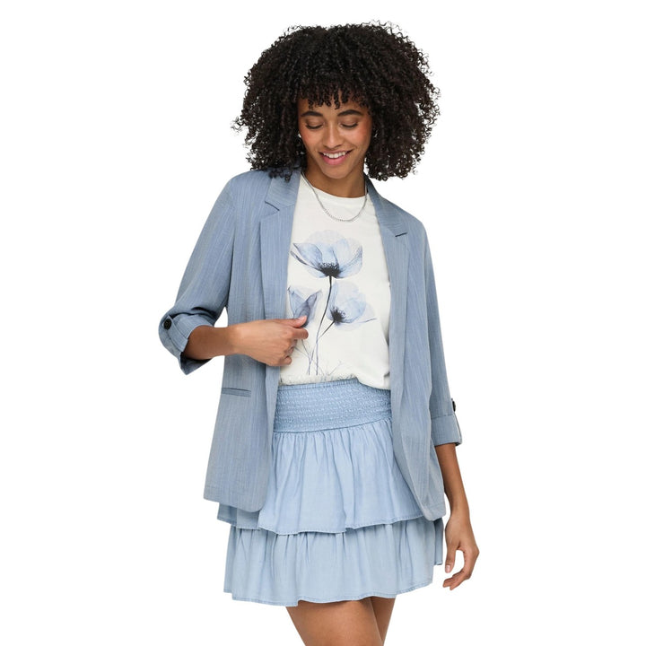 Image 1 : Femme portant un blazer Only bleu azur col revers et manches 3/4 retroussées, associé à un t-shirt fleuri blanc et une jupe courte bleu clair — Delvale